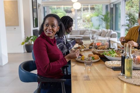 African american friends sharing relaxed home-cooked meal at modern open-plan dining table
