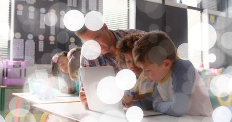 Teacher guiding elementary students on laptop for collaborative classroom learning