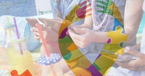 Colorful Autism Puzzle Ribbon Overlay on Friends Using Gadgets Outdoors
