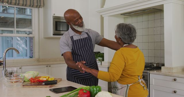 African american senior couple wearing aprons dancing together in the kitchen at home - Download Free Stock Photos Pikwizard.com