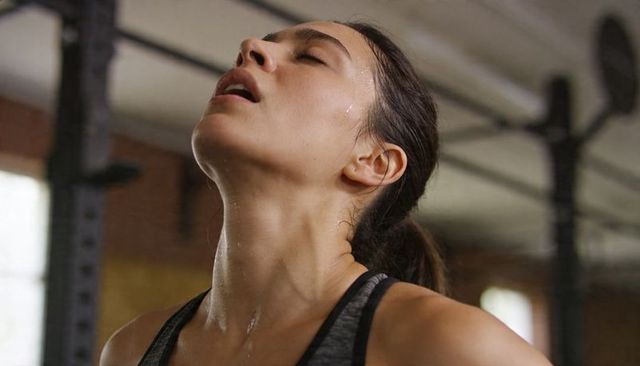 Elite female athlete catching breath after intense workout in industrial gym post-training recovery