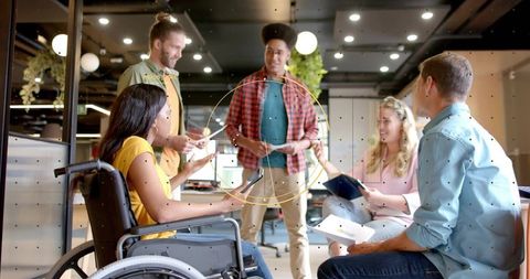 Diverse team collaborating in modern coworking lounge with wheelchair inclusion, casual brainstormin