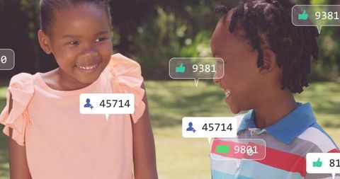 Smiling girl and boy sharing joyful moment with social media notifications in park