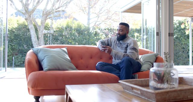 Man Relaxing on Orange Sofa in Bright Living Room - Download Free Stock Images Pikwizard.com