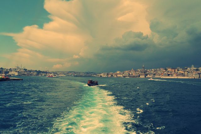 Storm clouds forming over Istanbul and the Bosphorus Strait creates a dramatic and moody skyline. Boats visible on water capturing the interplay of city and sea. Ideal for use in travel blogs, weather-related articles, tourism promotions, or dramatic landscape collections.