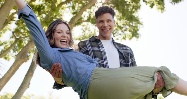 Couple enjoying time outside in sunny weather with trees in background. Perfect for use in lifestyle blogs, fitness advertising, and promotional material for outdoor events and activities.