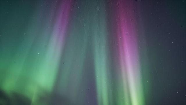 Dancing aurora borealis glowing green and magenta curtains over arctic night horizon