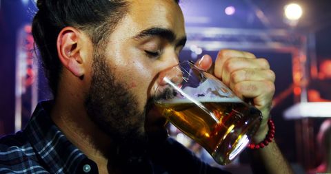 Young Man Drinking Beer in Energetic Nightclub Atmosphere