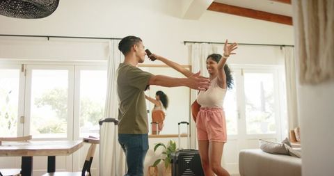 African american couple embracing in sunlit living room during homecoming with suitcase