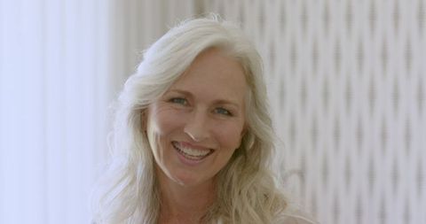 Smiling mature woman with long white hair exuding confidence