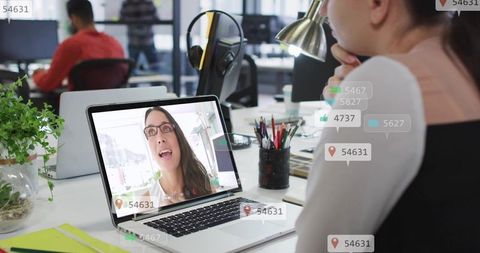 Young professional watching laptop video call with social media overlays in modern office