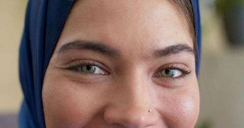 Closeup portrait indian woman wearing navy headscarf showing green-hazel eyes and nose stud