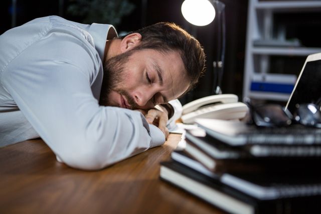 Tired businessman sleeping on the desk in office at night