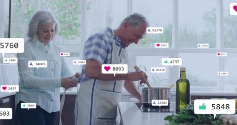 Senior couple livestreaming cooking demo in bright kitchen with social media badges