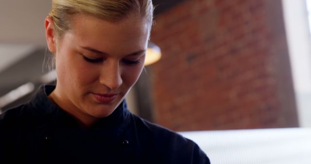 Young female chef concentrating while preparing a dish in a professional kitchen. Ideal for use in articles about female chefs, culinary education, training programs, restaurants, or cooking classes.