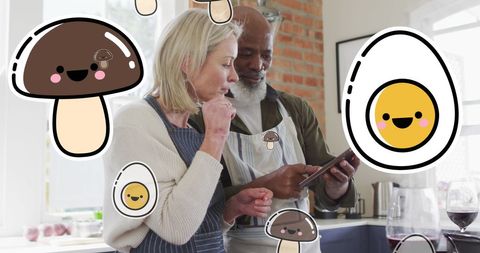 Happy couple in kitchen with playful food icons and tablet