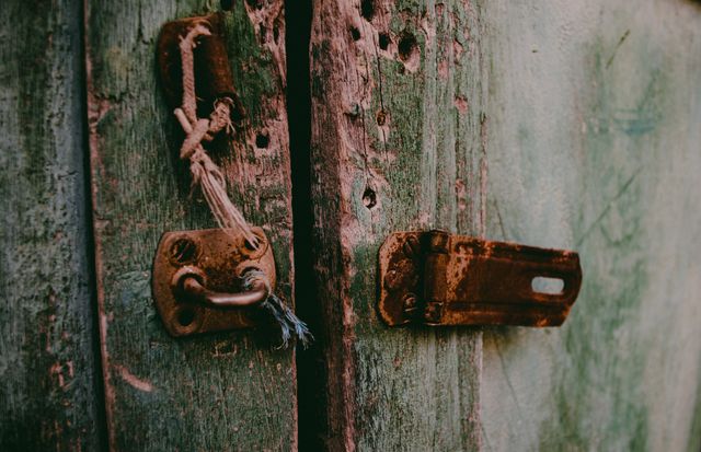 This image of a rustic wooden door with a weathered lock and rope offers a textured and antique feel. Perfect for use in design projects, backgrounds, or blog posts about countryside living, historical places, or DIY restoration projects.