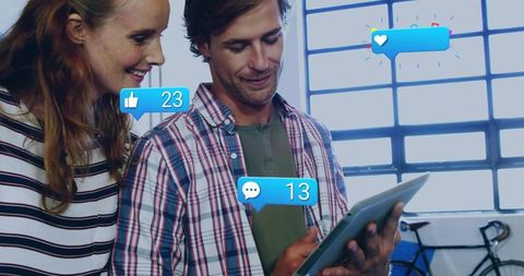 Young Professionals Collaborating on Tablet with Social Media Like and Comment Notifications