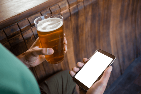 Man with transparent smartphone screen holding beer in rustic bar