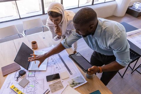 Diverse team collaborating on architectural blueprint at bright workspace