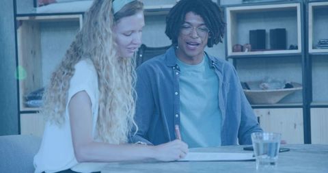 Young creative professionals collaborating while signing contract at modern coworking table