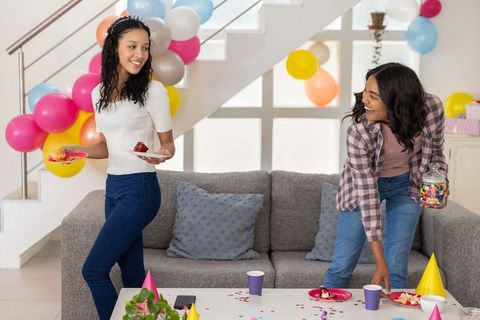Multicultural friends celebrating birthday party at home decorating with balloons and sweets