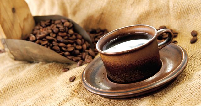 A rustic ceramic cup filled with coffee sits beside a scoop of coffee beans, with copy space - Download Free Stock Photos Pikwizard.com