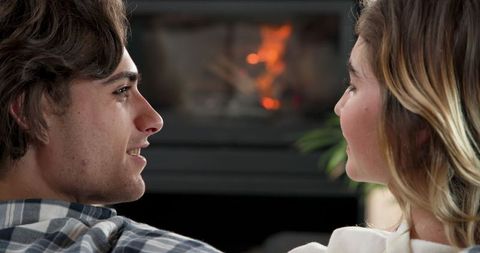 Relaxing Couple Chatting by Warm Fireplace in Cozy Living Room