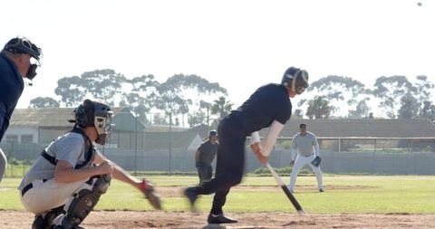 Batter swinging with catcher reaching and umpire watching on community baseball diamond