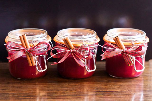 Homemade cranberry sauce in jars adorned with festive ribbons and cinnamon sticks. Ideal for holiday and Christmas-themed projects. Perfect for illustrating concepts of homemade gifts, traditional holiday recipes, or rustic decor.