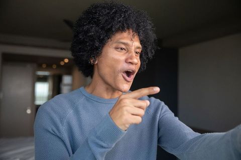 Smiling man in cozy bedroom environment with afro textured hair