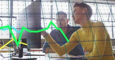 Woman pointing at data chart while colleague studying analytics on desktop monitor
