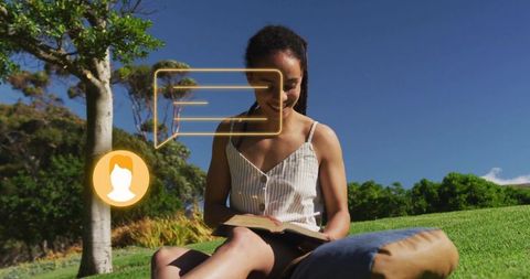 Young woman reading book on park lawn with augmented reality chat overlays and bright sunshine