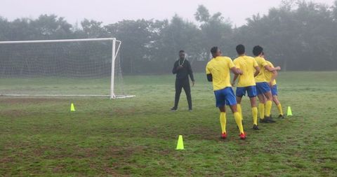 Soccer Coach Leads Team Training on Foggy Morning Field