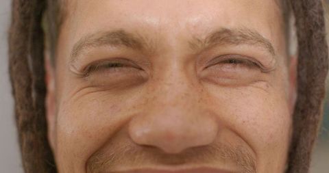 Freckled african american man grinning and squinting with dreadlocks closeup portrait