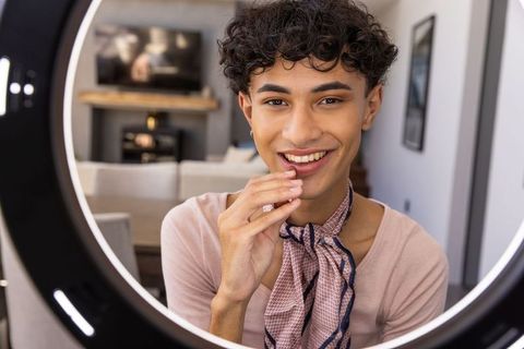 Confident young adult recording content with led ring light at home