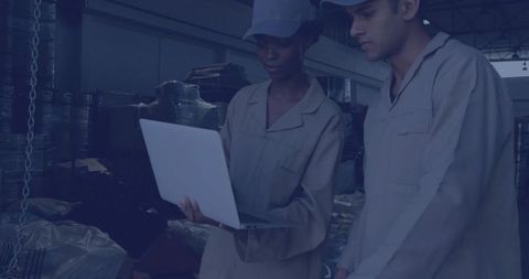 Warehouse Technicians Collaborating on Laptop in Industrial Setting