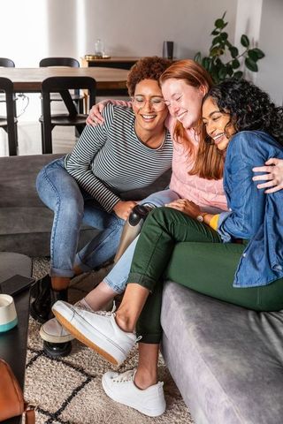 Diverse Female Friends Relaxing on Sofa with Massager and Coffee
