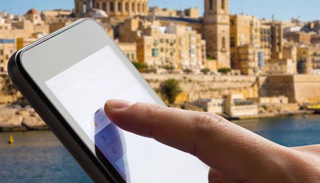 Tapping smartphone touchscreen with finger reflection over historic waterfront cityscape