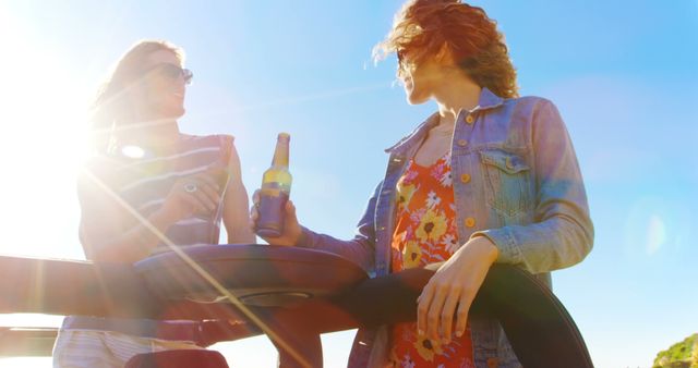 Two Women Enjoying a Sunny Day with Drinks Outdoors - Download Free Stock Images Pikwizard.com