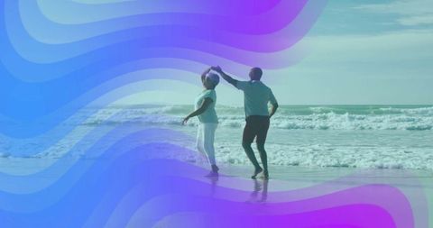 Joyful mature couple dancing on serene beach waves