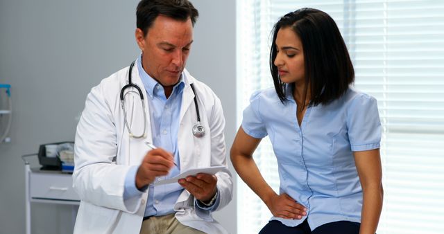 Doctor Consulting With Young Female Patient in Examination Room - Download Free Stock Images Pikwizard.com