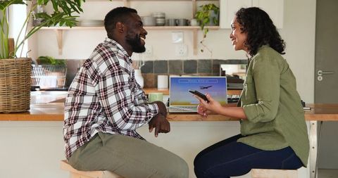 Couple Booking Flights Online in Modern Cozy Kitchen Setting