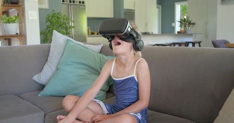 Young Girl Experiencing Virtual Reality on Couch Wearing Headset and Headphones