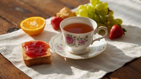 Vintage floral porcelain teacup with jam toast on sunlit rustic breakfast table