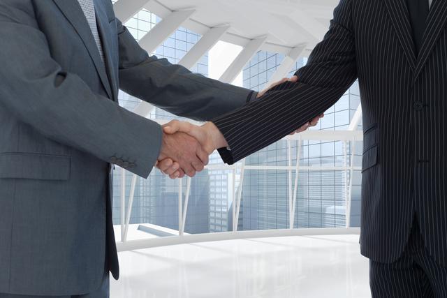 Business people shaking hands in modern office building signifies successful partnership and agreement. Ideal for use in business presentations, corporate brochures, websites, and networking event promotions, symbolizing teamwork, trust, and professional relationships.