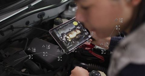Mechanic using tablet for engine diagnostics with augmented overlays in garage workshop