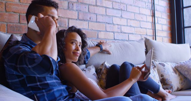 Happy Couple Relaxing on Couch with Smartphone and Tablet - Download Free Stock Images Pikwizard.com