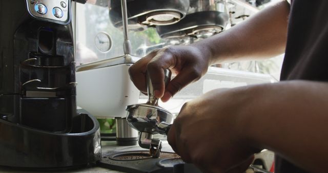Close up of african american male barista making coffee using coffe machine at cafe. small independent cafe business.
