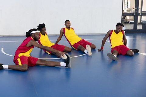 Team Basketball Players Stretching on Indoor Court